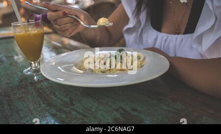 Spaghetti appetitosi sul piatto e succo sul tavolo. Da sopra gustosi tagliatelle fresche su piatto bianco e succo d'arancia in vetro Foto Stock