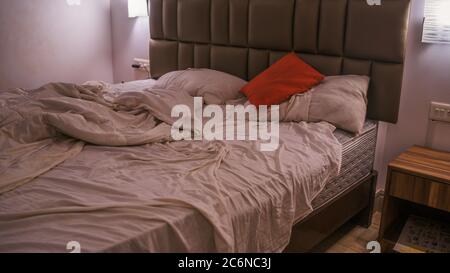 Letto non fatto in camera moderna. Da sopra calda coperta e morbidi cuscini collocati su comodi letti non fatti in elegante camera da letto contemporanea Foto Stock