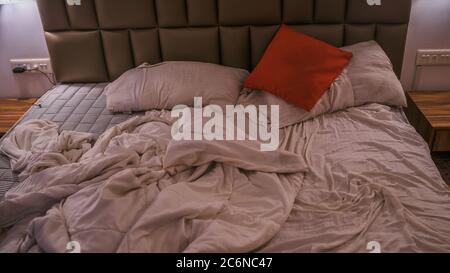 Letto non fatto in camera moderna. Da sopra calda coperta e morbidi cuscini collocati su comodi letti non fatti in elegante camera da letto contemporanea Foto Stock