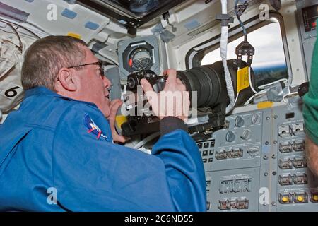 (13 gennaio 1997) --- l'astronauta Michael A. Baker, comandante di missione, usa una macchina fotografica di 35mm per fotografare un bersaglio di opportunità sulla Terra dal ponte di volo di poppa di Atlantis dello Space Shuttle. Baker e cinque compagni di equipaggio attracceranno alla stazione spaziale russa Mir verso la metà della settimana. Questa immagine è stata registrata con una fotocamera elettronica (ESC) e successivamente è stata downlinkata ai controllori di volo a Houston, Texas. Un secondo ESC, dedicato ad un progetto educativo e geografico chiamato Kidsat, è montato nel porto di osservazione sopra la testa di Baker. Foto Stock