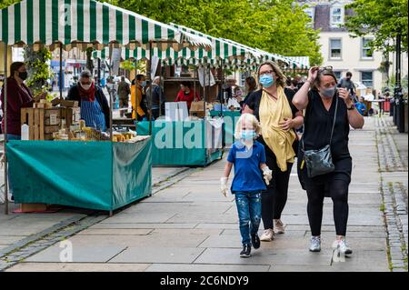 Haddington, East Lothian, Scozia, Regno Unito, 11 luglio 2020. Farmers Market riparte nella fase 3: Il popolare mercato all'aperto mensile si tiene per la prima volta da quando è stato bloccato con la gente del posto desiderosa di sostenere i produttori alimentari locali. Nonostante non sia obbligatorio all'aperto, la maggior parte delle persone indossa maschere facciali. Sono in vigore misure di distanza sociale. Una famiglia con un ragazzo giovane indossa maschere facciali Foto Stock