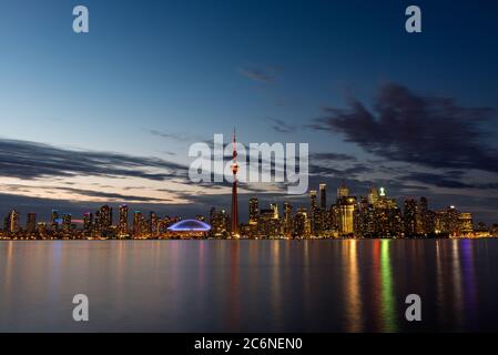 Illuminato sullo skyline di Toronto con il lago Ontario in primo piano, come si vede dal centro isola. Foto Stock