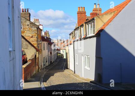 Cobbled Street con cielo blu e case a schiera a Whitby, North Yorkshire, Inghilterra, Regno Unito Foto Stock