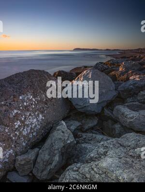 Vista panoramica del Monte San Bartolo e del Gabicce dalla spiaggia di Riccione all'alba, in Italia Foto Stock