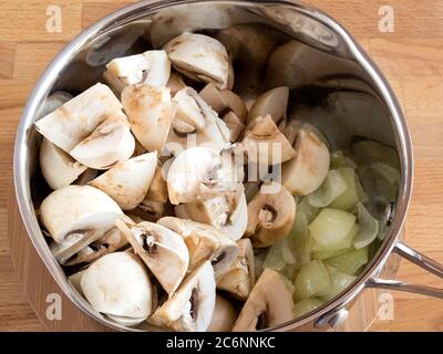 Aggiungere i funghi alle cipolle fritte nella padella. Zuppa di crema di cottura. Foto Stock