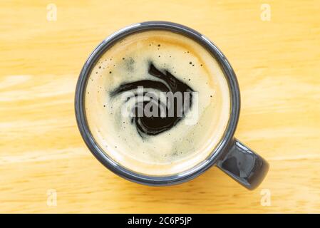 Caffè espresso e crema in tazza su tavola in legno con luce naturale Foto Stock