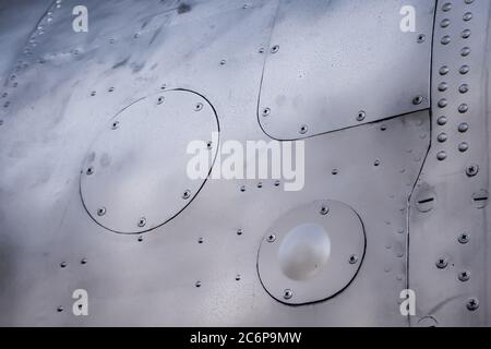 Primo piano della pelle dell'aeromobile. Rivetti su metallo grigio. Struttura in alluminio Foto Stock