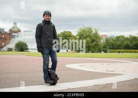 Glasgow, Scozia, Regno Unito. 11 Luglio 2020. Nella foto: Un locale è visto fuori cavalcando il suo uniciclo elettrico che indossa una maschera chirurgica blu che prende l'esercitazione in Glasgow Green durante il blocco allevato. Come gli scooter elettrici sono ora la norma, sono unicicles elettrici che stanno andando prendere sopra? Credit: Colin Fisher/Alamy Live News Foto Stock