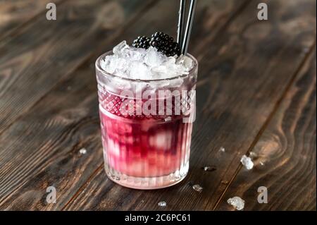 Bicchiere di cocktail Bramble fatto di gin, succo di limone, sciroppo di zucchero e crema di mure Foto Stock