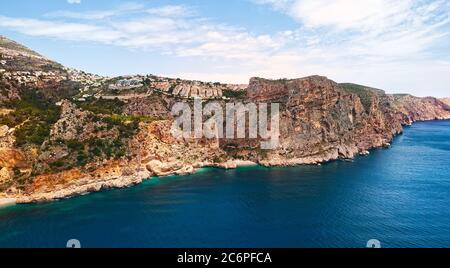 Foto aerea drone punto di vista pittoresca Cala del Moraig nella città costiera di Benitachell. Acque turchesi e luminose baia di sabbia bianca del Mar Mediterraneo Foto Stock