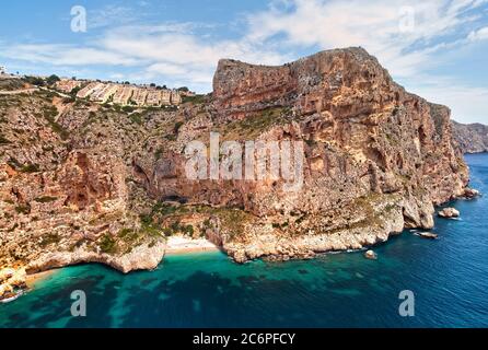 Foto aerea drone punto di vista pittoresca Cala del Moraig nella città costiera di Benitachell. Acque turchesi e luminose baia di sabbia bianca del Mar Mediterraneo Foto Stock