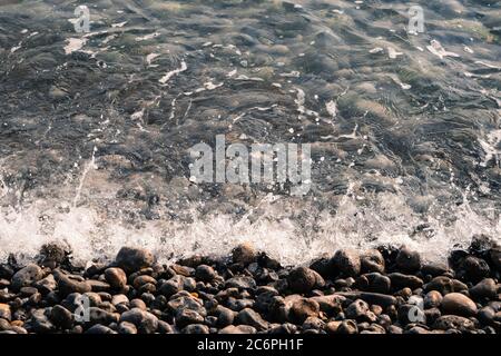 Immagine di sfondo di ciottoli sulla spiaggia, sul mare Foto Stock