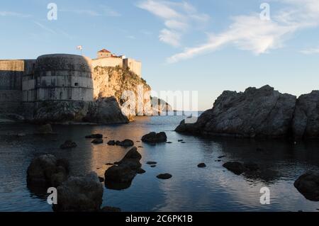 Le mura della città si affacciano sul mare di Dubrovnik e mostrano Fort Bokar costruito su roccia a strapiombo e circondato da mare Adriatico pulito Foto Stock