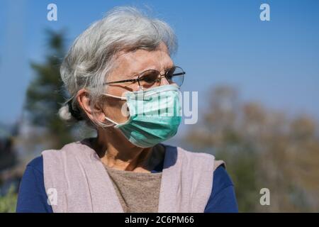 donna anziana con maschera facciale in piedi sulla terrazza Foto Stock