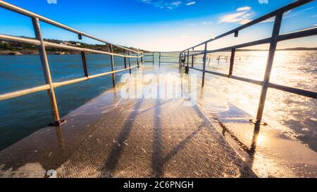 Il molo metallico è stato sommerso per metà nell'acqua del Mar baltico goteborg svezia che brilla di luce solare Foto Stock