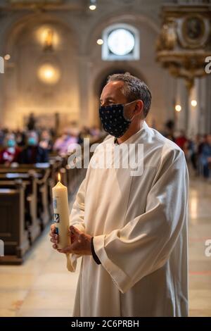 Monaco, Germania. 11 Luglio 2020. Una persona da battezzare si trova davanti all'altare con la candela battesimale illuminata. Undici adulti sono stati battezzati dal Cardinale nella Chiesa di San Michele. Credit: Lino Mirgeler/dpa/Alamy Live News Foto Stock