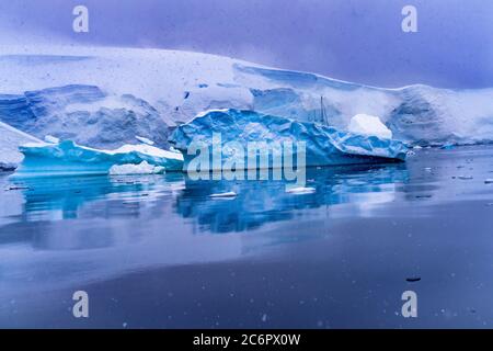 Nevoso Barca a vela iceberg Reflection Blue Glacier Snow Mountains Paradise Bay Skintorp Cove Antartide. Foto Stock