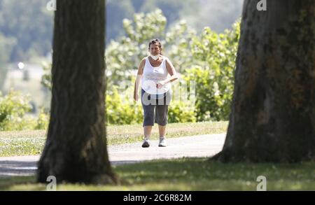 Cleveland, Stati Uniti. 11 Luglio 2020. Una donna cammina con la sua maschera intorno al collo in risposta all'ordine di copertura del viso dell'Ohio sulla scia del Coronavirus (COVID-19) all'Edgewater Park a Cleveland, Ohio, sabato 11 luglio 2020. Foto di Aaron Josefczyk/UPI Credit: UPI/Alamy Live News Foto Stock