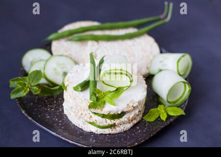 Cibo sano. Sandwich di riso con cetriolo e fagioli verdi. Torte di riso con formaggio cremoso, cetriolo ed erbe. Sandwich mattutino. CopySpace Foto Stock