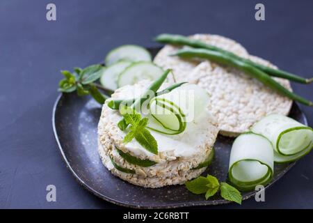 Cibo sano. Sandwich di riso con cetriolo e fagioli verdi. Torte di riso con formaggio cremoso, erbe aromatiche. Sandwich mattutino. CopySpace Foto Stock