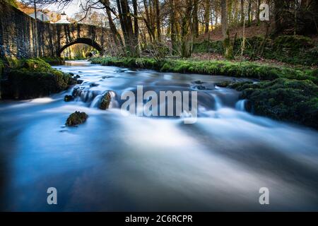 Force Beck attraversa il villaggio di Force Mills vicino a Grizedale in Cumbria. Foto Stock