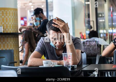 Portimao, Portogallo - 11 luglio 2020: Un uomo con una sigaretta e una maschera protettiva che guarda triste e disperato. Foto Stock