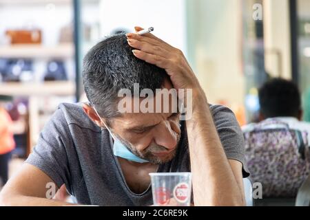 Portimao, Portogallo - 11 luglio 2020: Un uomo con una sigaretta che ha un aspetto triste e disperato. Foto Stock