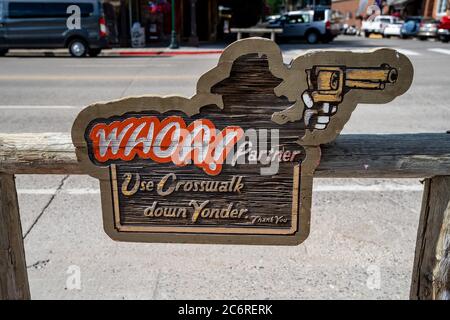 Jackson, Wyoming - 27 giugno 2020: Segno con un tema selvaggio West pistola e cowboy - Whoa Partner, utilizzare Crosswalk giù Yonder, impedendo jaywalking di touri Foto Stock