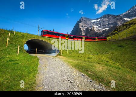 Treno turistico a cremagliera rosso sulla ferrovia di montagna sopra il tunnel. Grandi escursioni e luoghi di viaggio nelle Alpi svizzere, Jungfraujoch, Oberlan Bernese Foto Stock