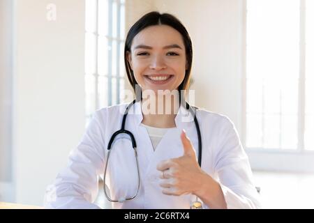Testa ritratto scatto sorridente medico femminile mostrando pollice in su Foto Stock