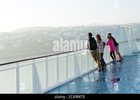 La gente guarda la costa nebbiosa in piedi su un ponte della nave Foto Stock