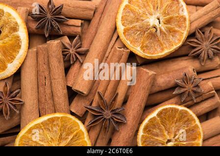 Concetto di bevanda di tè delle feste invernali. Macro foto di bastoncini di cannella fette di arancia essiccate e sfondo di stelle di anice Foto Stock