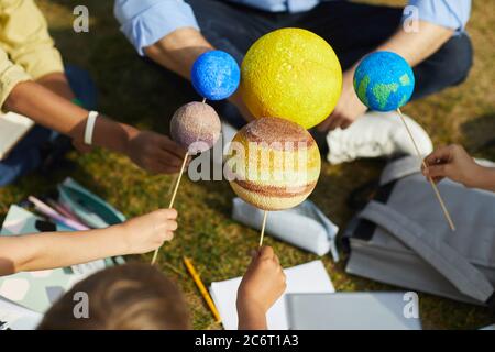 Primo piano di gruppo di bambini che tengono pianeti modello mentre godendo di classe di astronomia all'aperto in luce del sole, spazio di copia Foto Stock