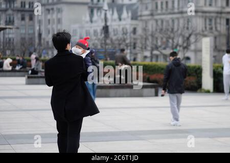 Padre e bambino che indossa una maschera chirurgica che cammina nel bund di Shanghai Foto Stock