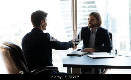 Due partner commerciali felici che si scuotono le mani durante la riunione. Foto Stock