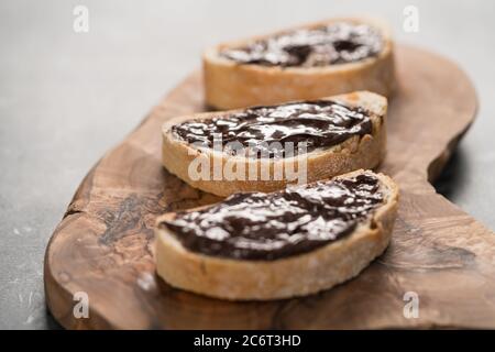 Ciabatta rustica con crema di cioccolato biologica su tavola di ulivo Foto Stock