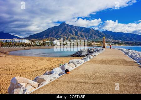 Spiaggia, mare, passeggiata e montagne, scenario di vacanza estiva a Puerto Banus resort sulla Costa del Sol a Marbella, Andalusia, Provincia di Malaga, Spagna Foto Stock