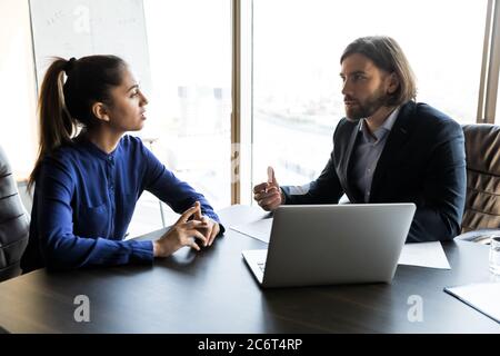 Un capo giovane e serio che parla con una donna. Foto Stock