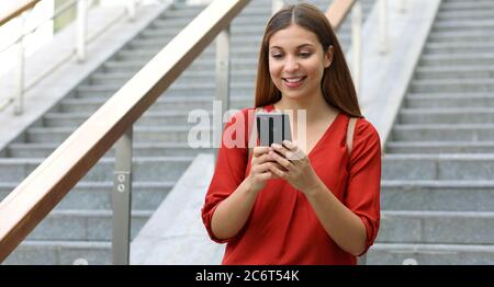 Ritratto di bella donna di affari che tiene lo smartphone camminando giù le scale Foto Stock