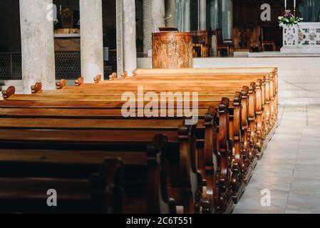 Cattedrale silenziosa e vuota con file di panchine di legno sotto i raggi del tramonto Foto Stock