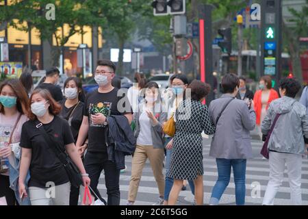 I giovani camminano sulla traversata zebra, indossando la maschera facciale per evitare il coronavirus covid-19 Foto Stock