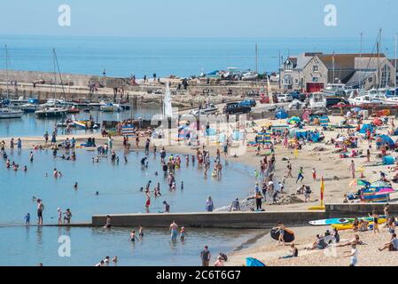 Lyme Regis, Dorset, Regno Unito. 12 luglio 2020. Regno Unito Meteo: Folle di beachgoers accorrono alla pittoresca località balneare di Lyme Regis per immergersi nel sole caldo e bruciante. Famiglie, visitatori e amanti del sole hanno fatto il pieno di spiaggia questo fine settimana per godersi il meglio del tempo soleggiato mentre i turisti fanno un wlecome ritorno alla popolare località. Credit: Celia McMahon/Alamy Live News Foto Stock