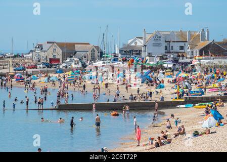 Lyme Regis, Dorset, Regno Unito. 12 luglio 2020. Regno Unito Meteo: Folle di beachgoers accorrono alla pittoresca località balneare di Lyme Regis per immergersi nel sole caldo e bruciante. Famiglie, visitatori e amanti del sole hanno fatto il pieno di spiaggia questo fine settimana per godersi il meglio del tempo soleggiato mentre i turisti fanno un wlecome ritorno alla popolare località. Credit: Celia McMahon/Alamy Live News Foto Stock