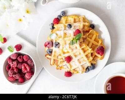 Waffle belgi con lamponi, mirtilli, cagliata e tè, vista dall'alto. Foto Stock