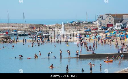 Lyme Regis, Dorset, Regno Unito. 12 luglio 2020. Regno Unito Meteo: Folle di beachgoers accorrono alla pittoresca località balneare di Lyme Regis per immergersi nel sole caldo e bruciante. Famiglie, visitatori e amanti del sole hanno fatto il pieno di spiaggia questo fine settimana per godersi il meglio del tempo soleggiato mentre i turisti fanno un wlecome ritorno alla popolare località. Credit: Celia McMahon/Alamy Live News Foto Stock