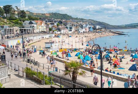 Lyme Regis, Dorset, Regno Unito. 12 luglio 2020. Regno Unito Meteo: Folle di beachgoers accorrono alla pittoresca località balneare di Lyme Regis per immergersi nel sole caldo e bruciante. Famiglie, visitatori e amanti del sole hanno fatto il pieno di spiaggia questo fine settimana per godersi il meglio del tempo soleggiato mentre i turisti fanno un wlecome ritorno alla popolare località. Credit: Celia McMahon/Alamy Live News Foto Stock