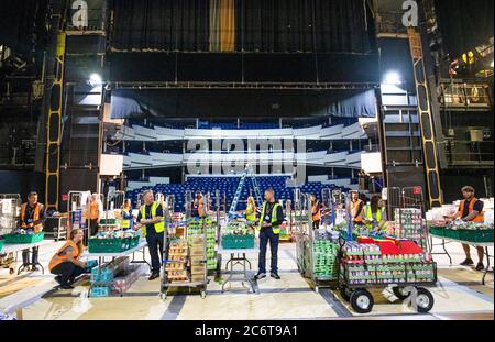 I membri del Consiglio delle Highlands impacchettano migliaia di pacchetti di cibo, con forniture per gli Highlanders che ancora schermano dalla pandemia del coronavirus, sul palco dell'Empire Theatre presso Eden Court a Inverness. Foto Stock