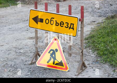 Segnale di avvertenza "funziona in anticipo" su strada. Segnaletica stradale di riparazione e il segno del Detour tradotto dalla lingua russa Foto Stock