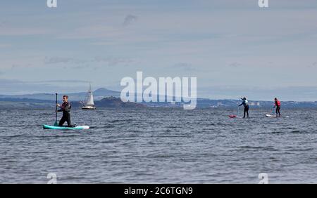 Portobello, Edimburgo, Scozia, UK 12 Luglio 2020. Temperatura 13 gradi al mattino che sale a 18 gradi al pomeriggio con poca brezza. Sport acquatici su tavole da paddle, kayak e barca a remi molto popolare negli ultimi tre mesi della pandemia di Coronavirus, come persone di tutte le età hanno più sano inseguimenti nel loro tempo libero, così come i nuotatori selvatici regolare facendo un tuffo nel Firth of Forth. Foto Stock