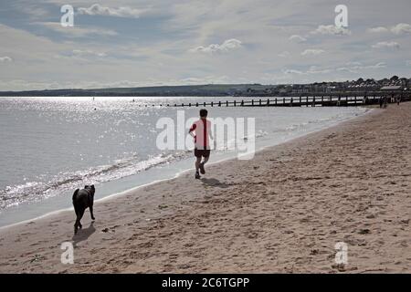 Portobello, Edimburgo, Scozia, UK 12 Luglio 2020. Temperatura 13 gradi al mattino che sale a 18 gradi al pomeriggio con poca brezza. Uomo ritratto che corre con il suo cane in inseguimento molto popolare negli ultimi tre mesi della pandemia di Coronavirus come persone di tutte le età hanno inseguimenti più sani nel loro tempo libero. Foto Stock